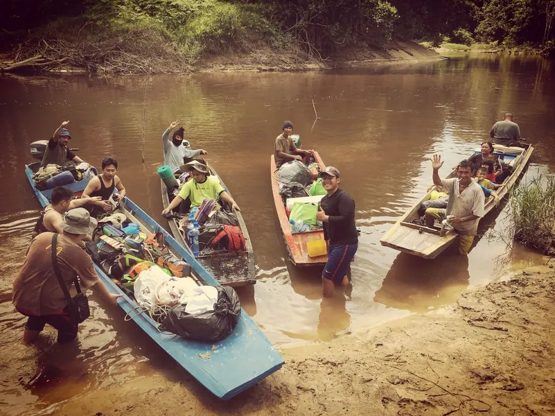 Boats and travelling companions gathered on a jungle riverbank in Borneo